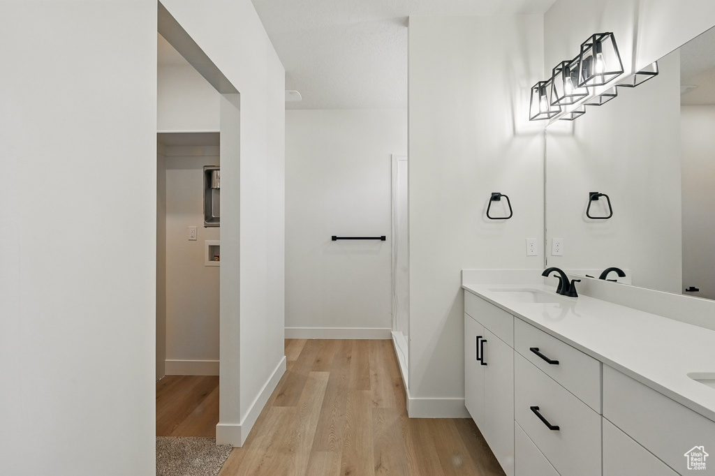 Full bath with wood finished floors, double vanity, and baseboards