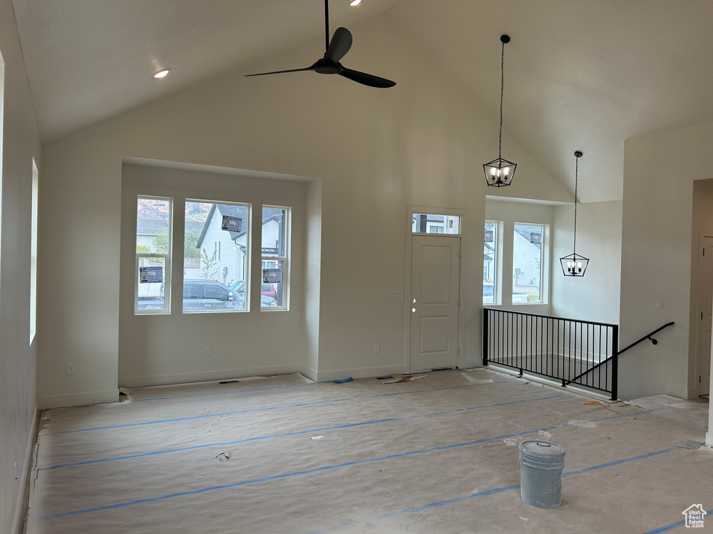 Unfurnished living room with high vaulted ceiling, ceiling fan, and baseboards