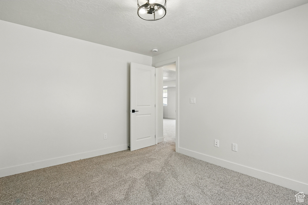 Unfurnished room with carpet, baseboards, a textured ceiling, and a smoke detector