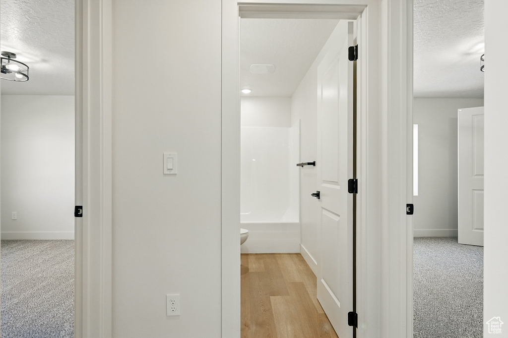 Hall featuring a textured ceiling and baseboards
