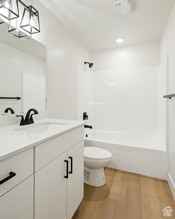 Bathroom with wood finished floors, vanity, toilet, bathtub / shower combination, and recessed lighting