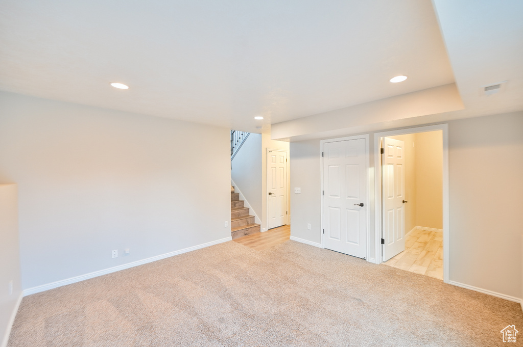 Finished below grade area with light carpet, recessed lighting, stairway, and baseboards