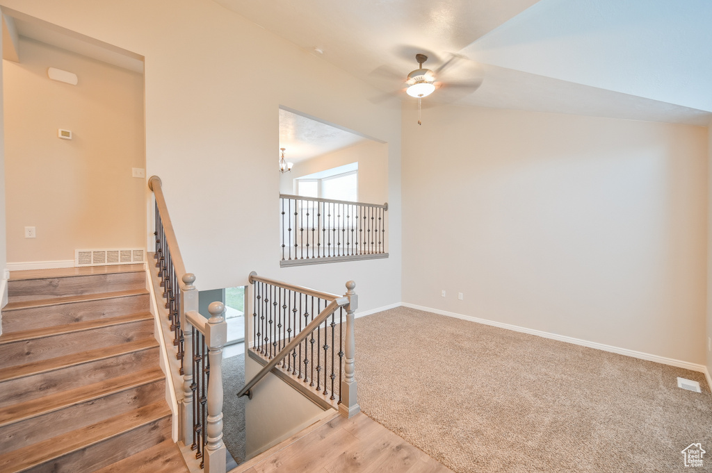 Staircase with a ceiling fan, baseboards, and wood finished floors