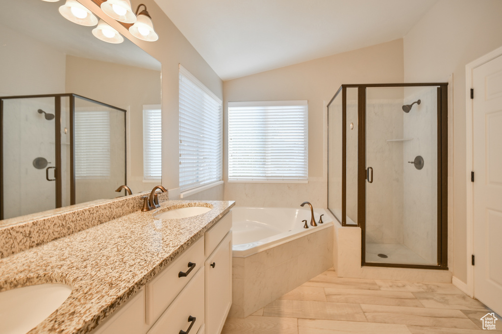Bathroom featuring lofted ceiling, a garden tub, double vanity, and a stall shower