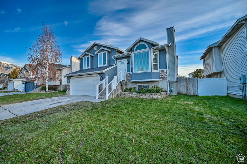 View of front of home featuring driveway, a garage, a chimney, stucco siding, and a residential view