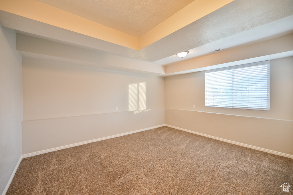 Carpeted empty room featuring baseboards and a textured ceiling