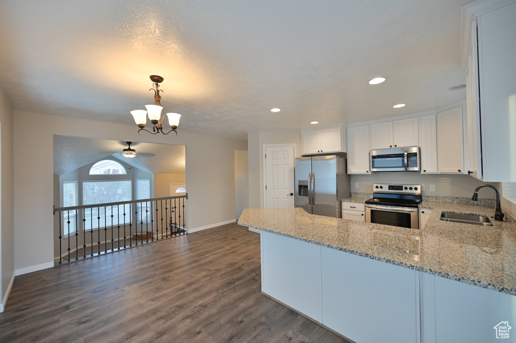 Kitchen with stainless steel appliances, a sink, baseboards, a peninsula, and light stone countertops