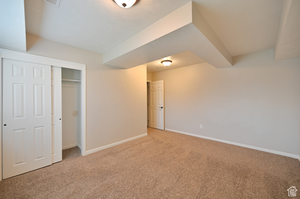 Unfurnished bedroom featuring light colored carpet, baseboards, and a closet