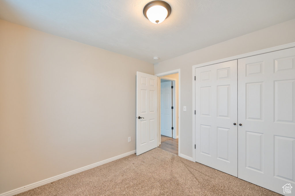 Unfurnished bedroom with light colored carpet, baseboards, and a closet