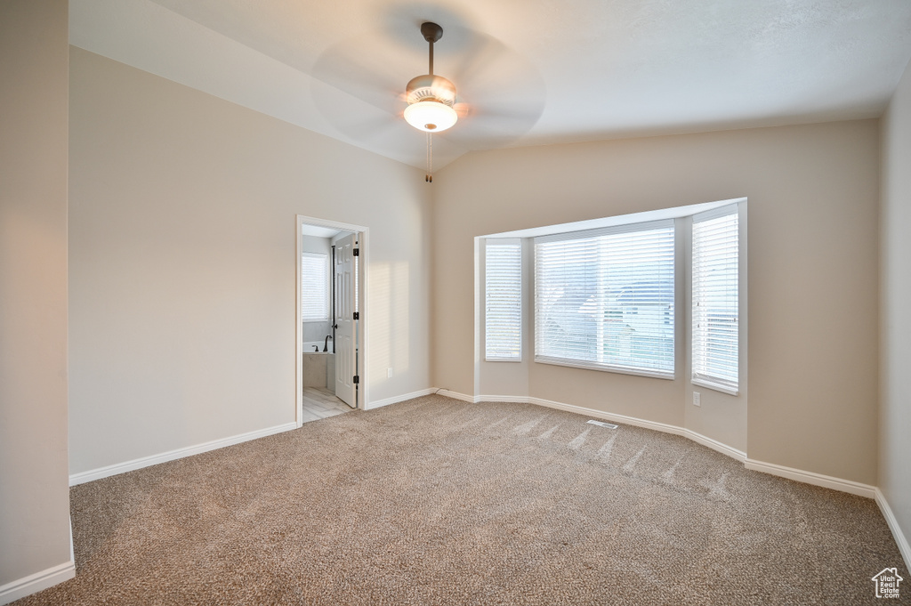 Empty room featuring light carpet, ceiling fan, and baseboards