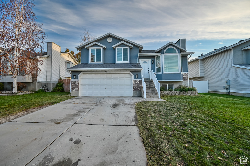 View of front facade with stucco siding, an attached garage, concrete driveway, and stone siding