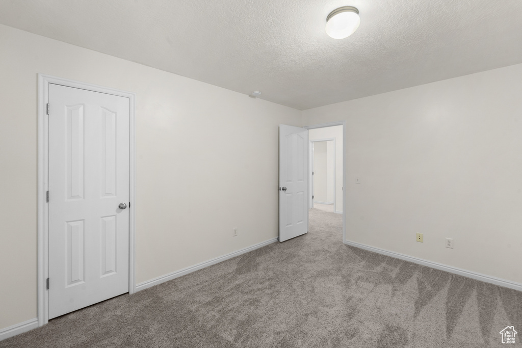 Unfurnished bedroom featuring carpet flooring, baseboards, and a textured ceiling