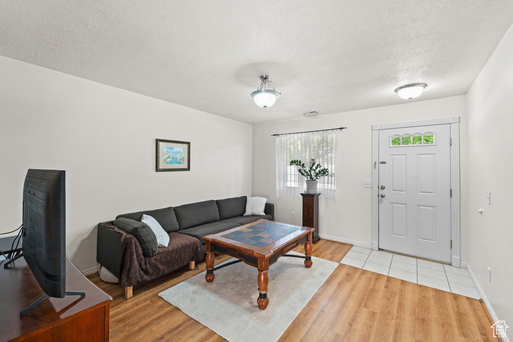 Living area featuring light wood finished floors, a textured ceiling, and baseboards