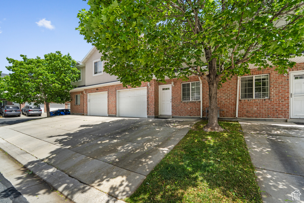 Obstructed view of property featuring driveway, a garage, and brick siding