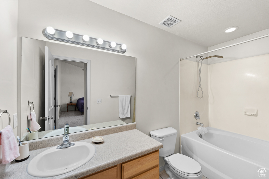 Bathroom featuring vanity, toilet, and washtub / shower combination