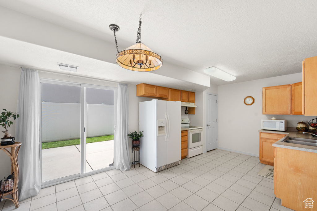 Kitchen featuring white appliances, a sink, under cabinet range hood, a textured ceiling, and light brown cabinetry