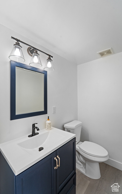 Half bath featuring wood finished floors, toilet, and vanity