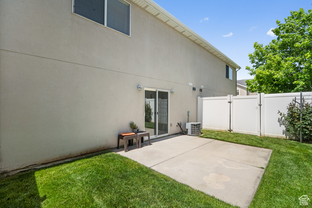 Rear view of house with central air condition unit, a gate, a patio area, and stucco siding