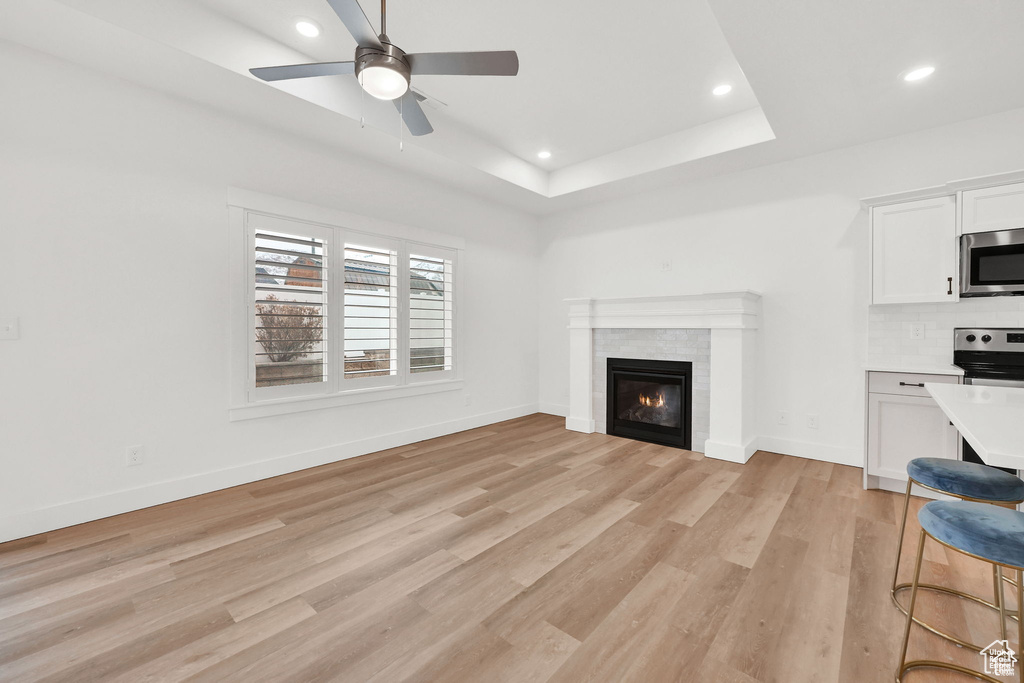 Unfurnished living room featuring light wood-type flooring, recessed lighting, ceiling fan, a fireplace, and baseboards