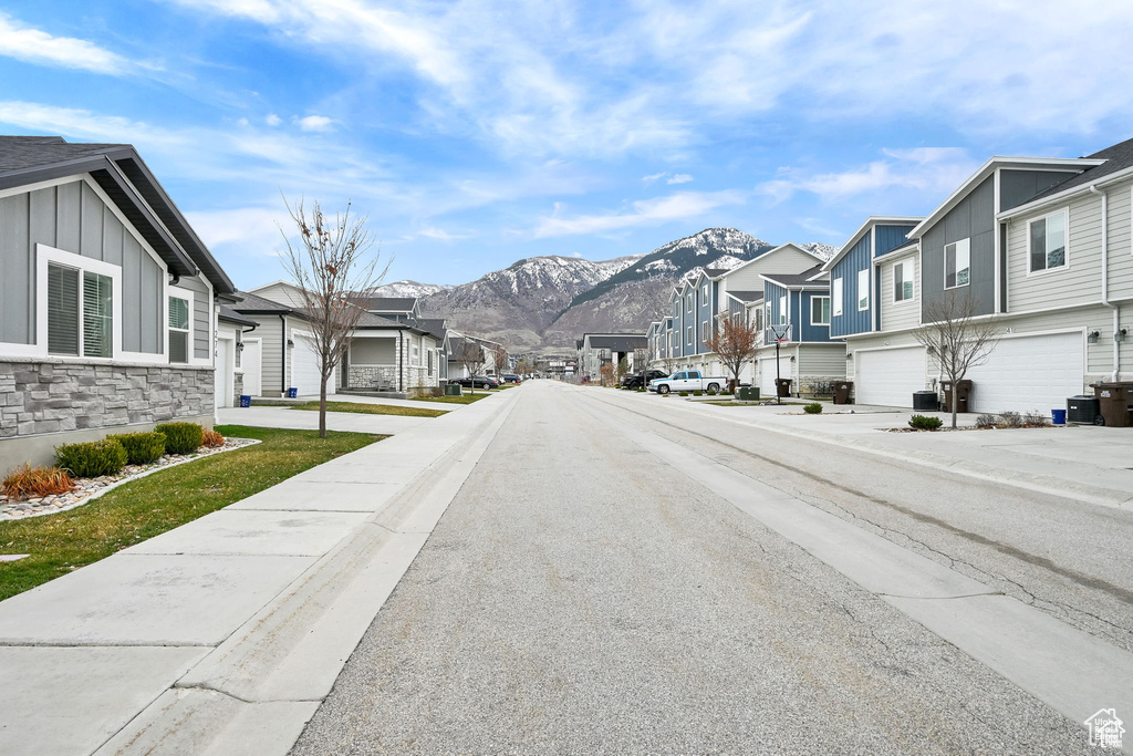 View of asphalt road featuring a residential view, a mountain view, and sidewalks