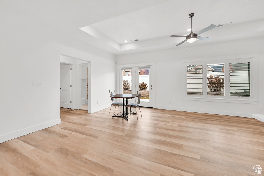 Living room featuring a ceiling fan, light wood-style flooring, baseboards, a tray ceiling, and recessed lighting