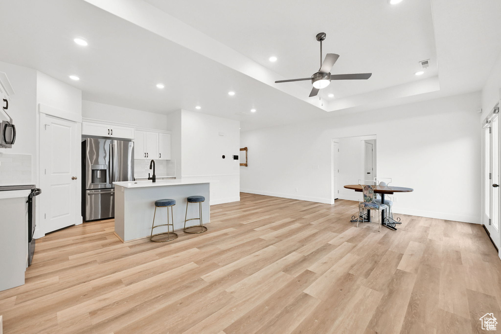 Unfurnished living room featuring recessed lighting, a ceiling fan, light wood finished floors, a sink, and baseboards