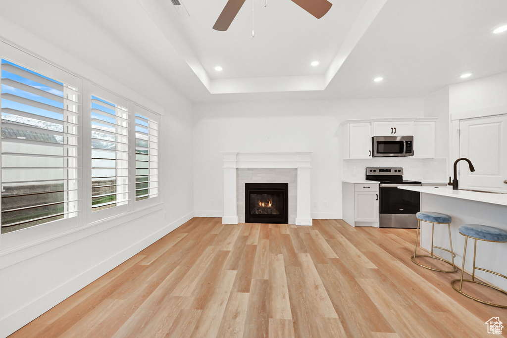 Unfurnished living room with a sink, healthy amount of natural light, ceiling fan, light wood-style floors, and recessed lighting