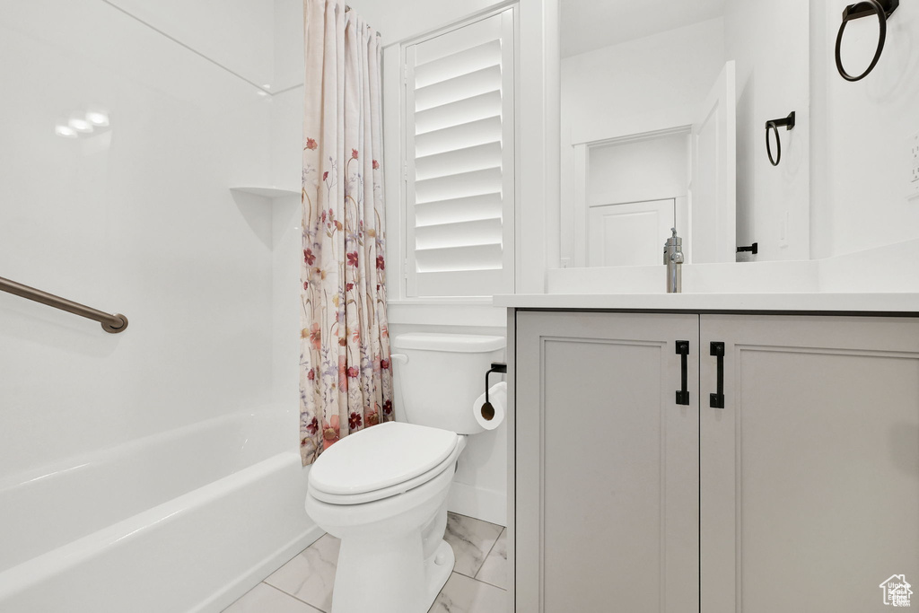 Full bathroom featuring toilet, marble finish flooring, vanity, and shower / bath combo with shower curtain