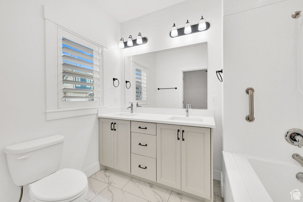 Full bathroom with marble look tile flooring, toilet, double vanity, and baseboards