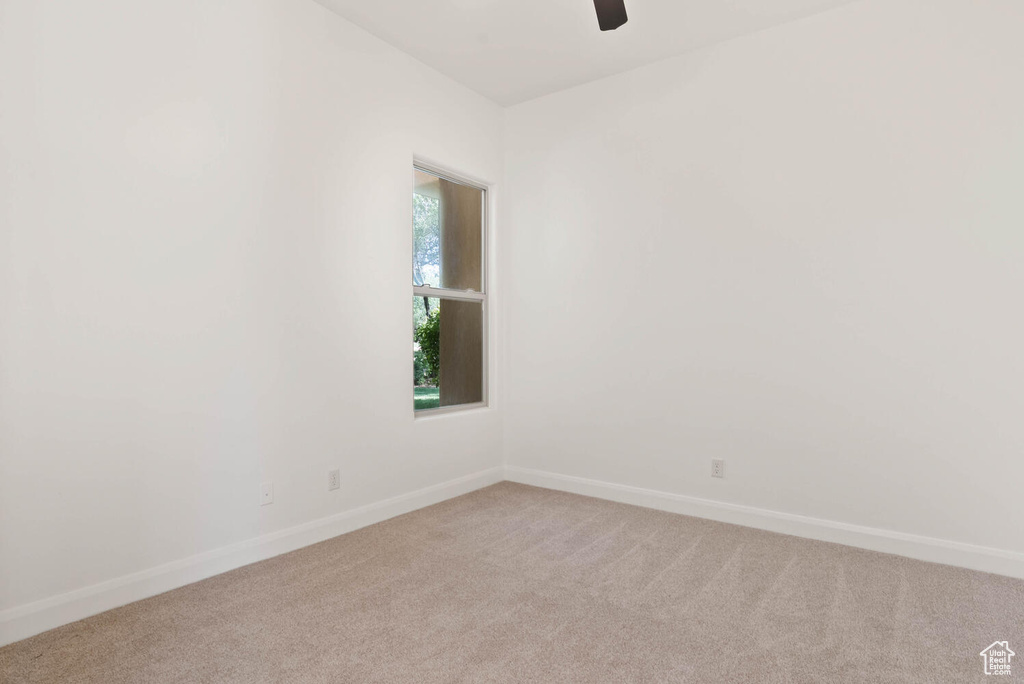 Spare room with light colored carpet, baseboards, and a ceiling fan