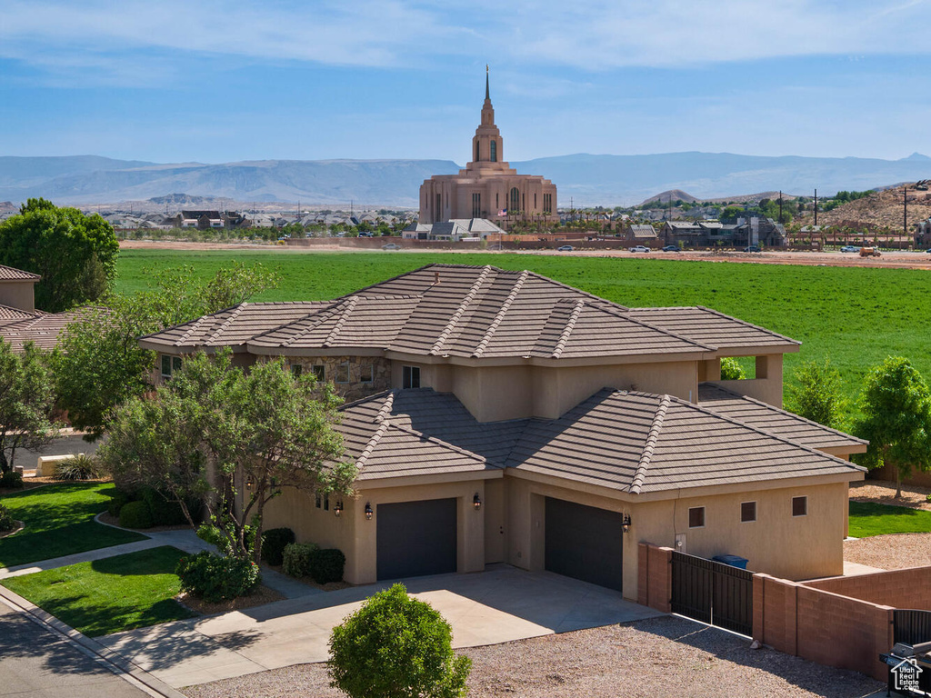 View of front of house with a tiled roof, a mountain view, driveway, and stucco siding