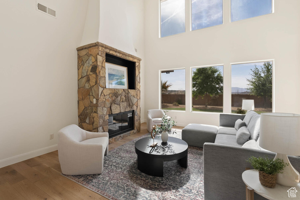 Living room featuring a fireplace, wood finished floors, baseboards, and a towering ceiling