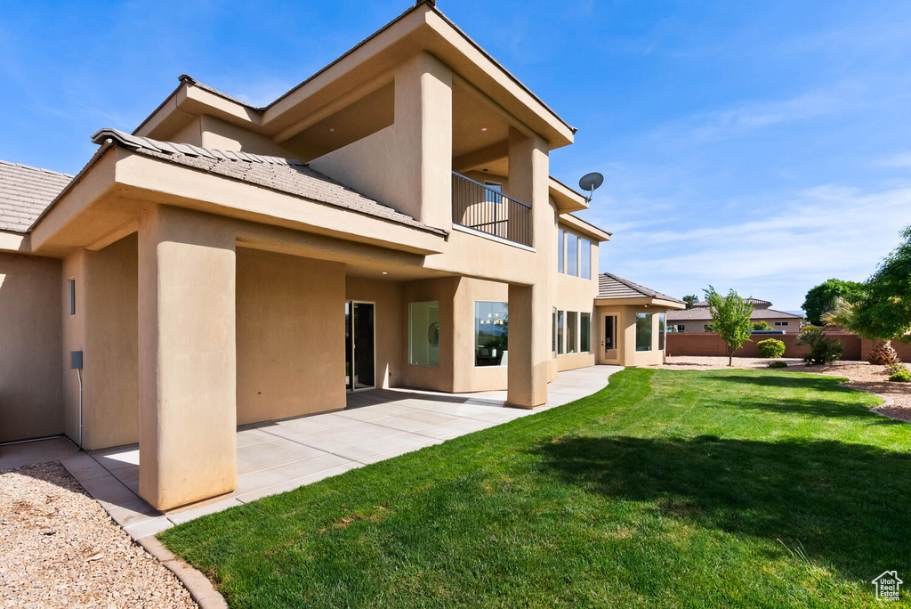 Rear view of property with stucco siding, a balcony, a patio, and a tile roof
