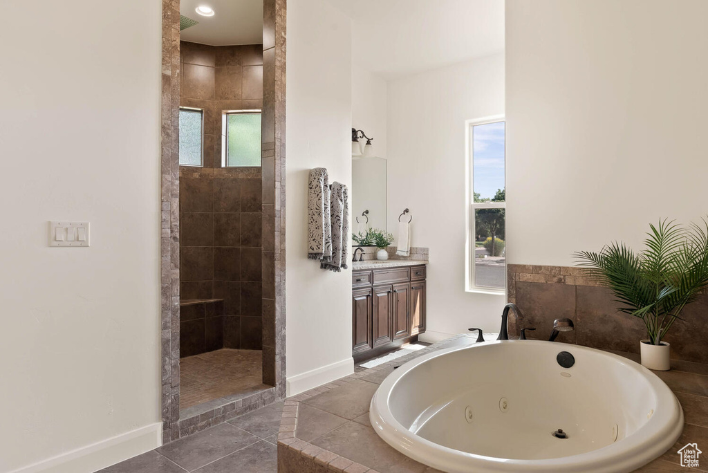 Bathroom with a tub with jets, baseboards, walk in shower, and vanity