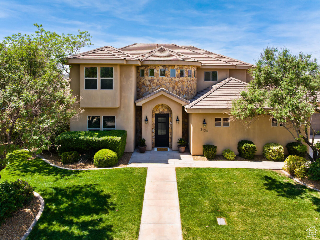 Mediterranean / spanish home with stucco siding, a front lawn, and a tile roof