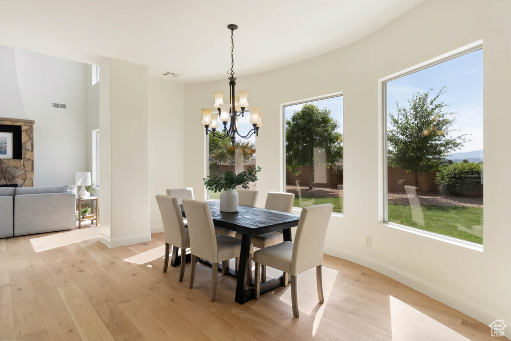 Dining room with light wood-style floors, a chandelier, baseboards, and a fireplace