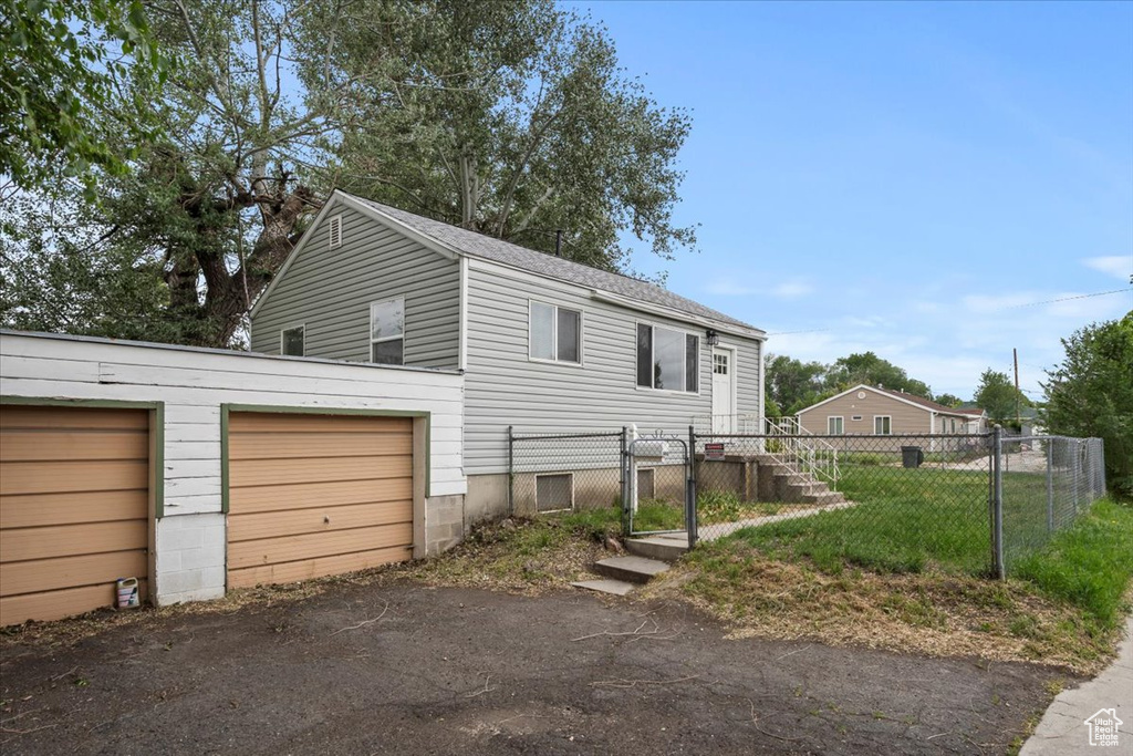 View of property exterior with a garage, fence, and driveway