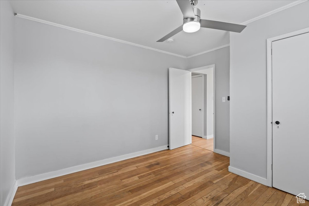 Unfurnished bedroom featuring crown molding, light wood-style flooring, baseboards, and a ceiling fan