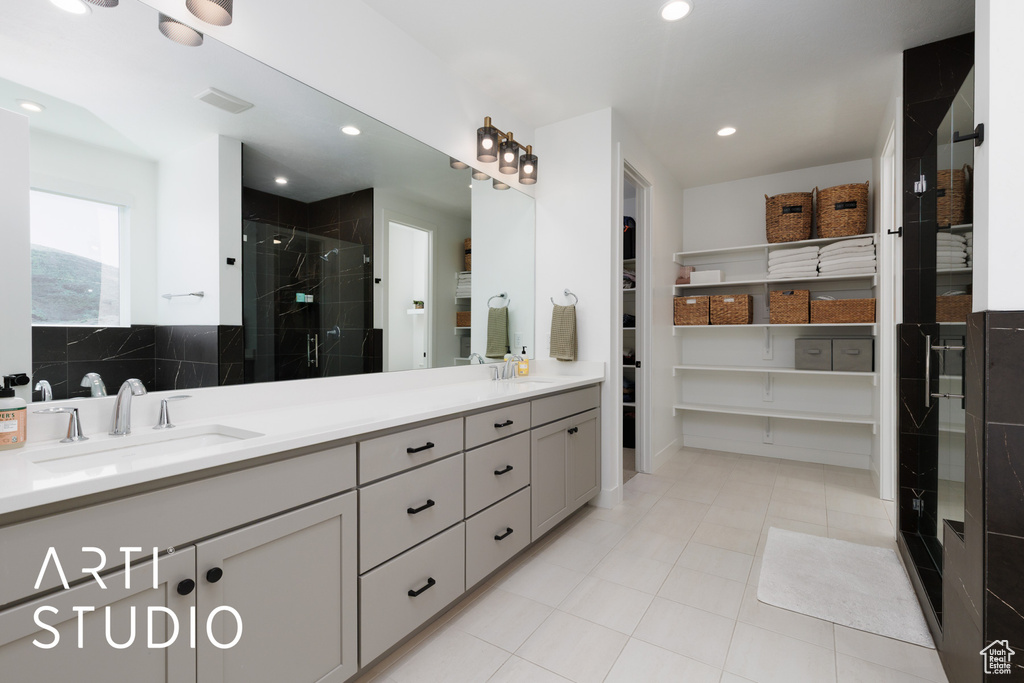 Bathroom with double vanity, visible vents, a shower stall, and a sink