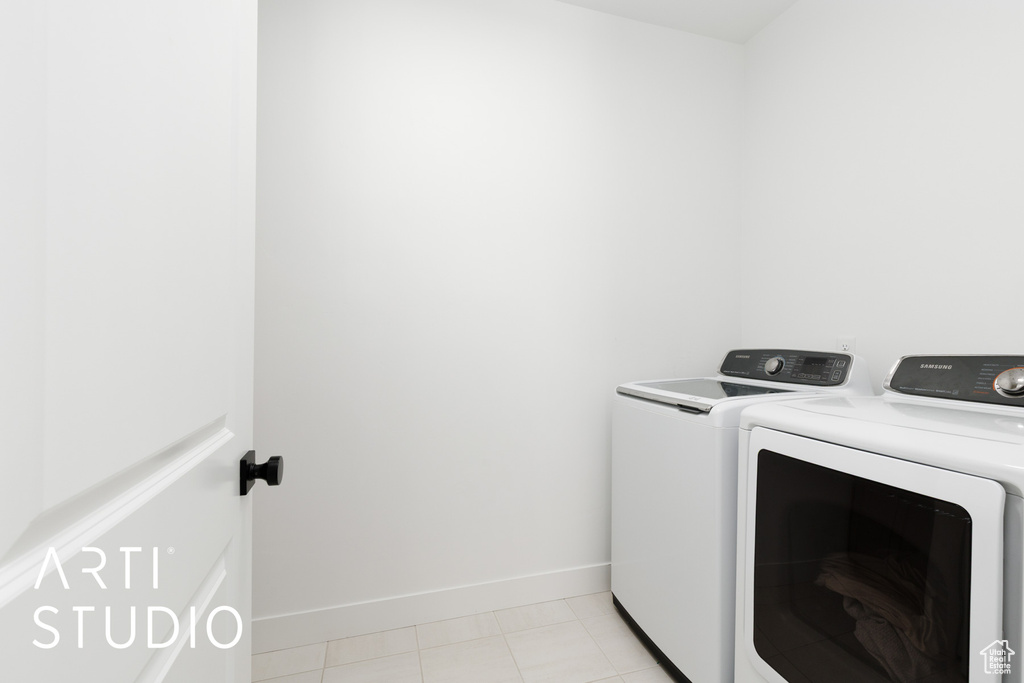 Laundry room featuring light tile patterned floors, baseboards, laundry area, and washer and dryer
