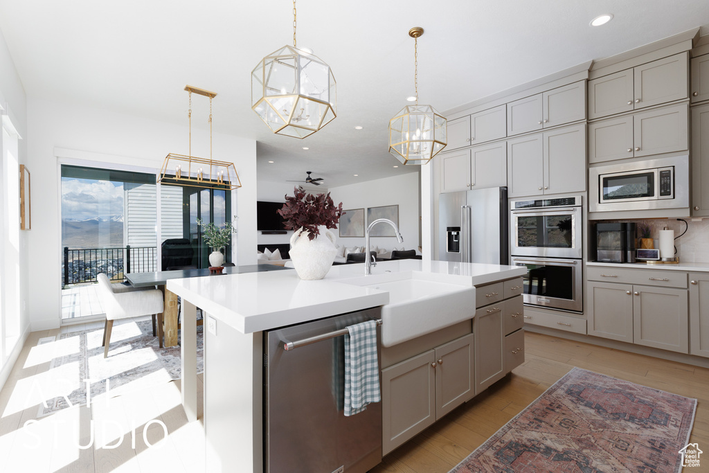 Kitchen with a sink, appliances with stainless steel finishes, a notable chandelier, and gray cabinetry