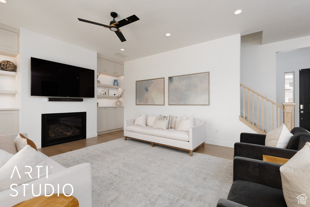 Living area with a glass covered fireplace, recessed lighting, a ceiling fan, and light wood-type flooring