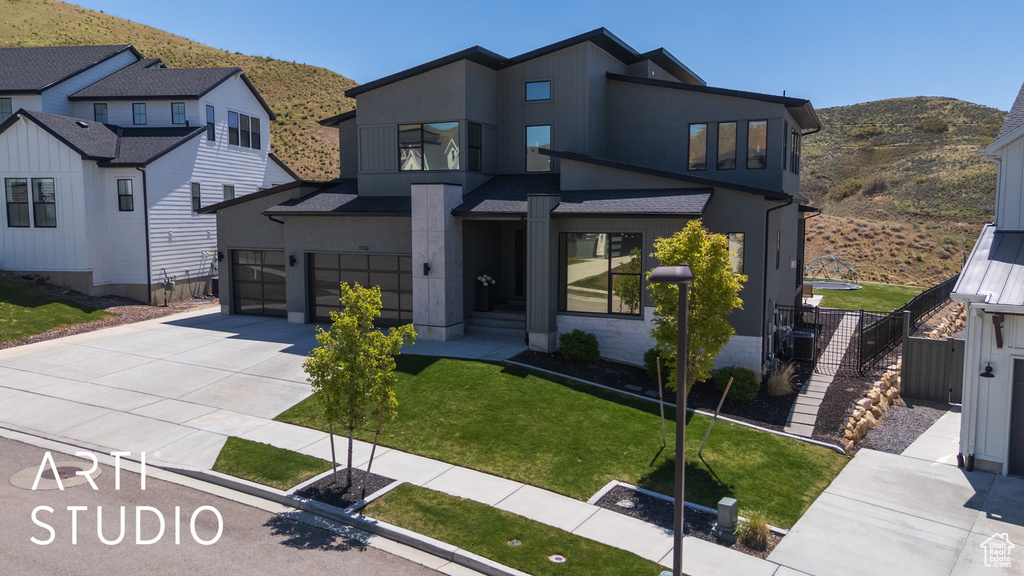 Contemporary home featuring fence, a front yard, stucco siding, a mountain view, and driveway