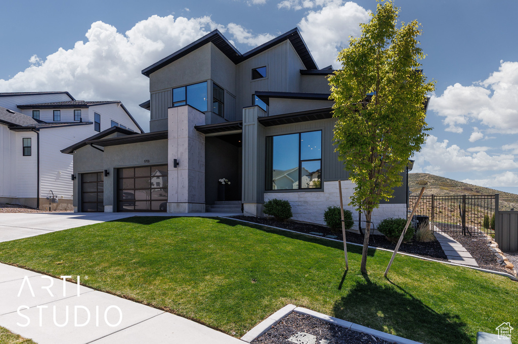 Modern home featuring a front lawn, fence, and driveway