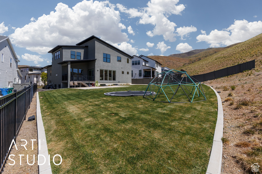 View of yard featuring a fenced backyard, a trampoline, and a mountain view