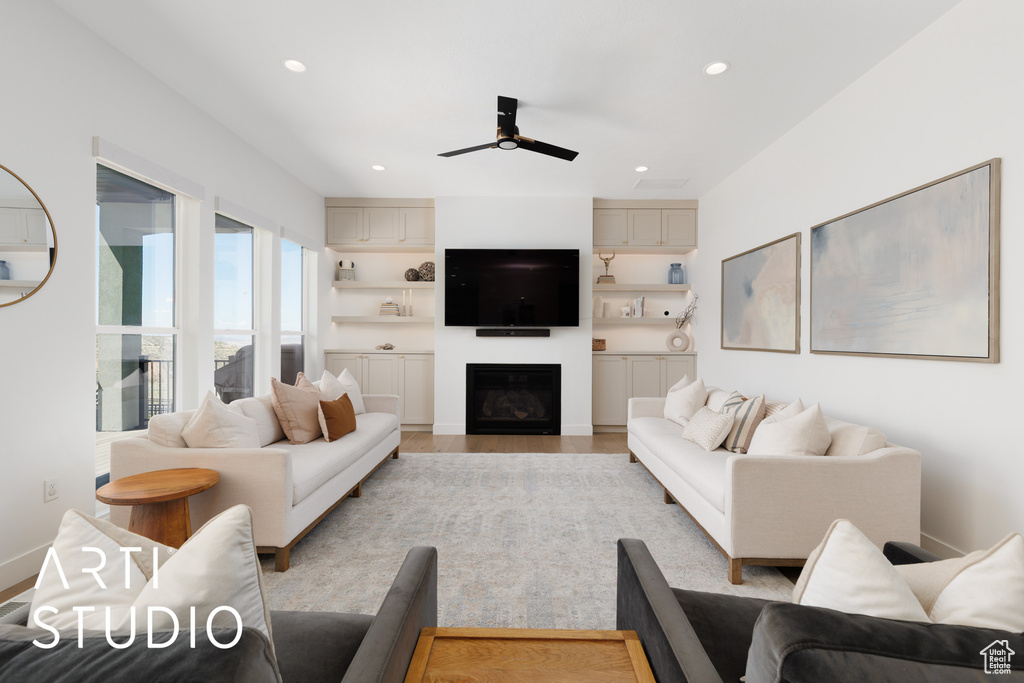 Living area featuring a fireplace, light wood finished floors, a ceiling fan, and recessed lighting