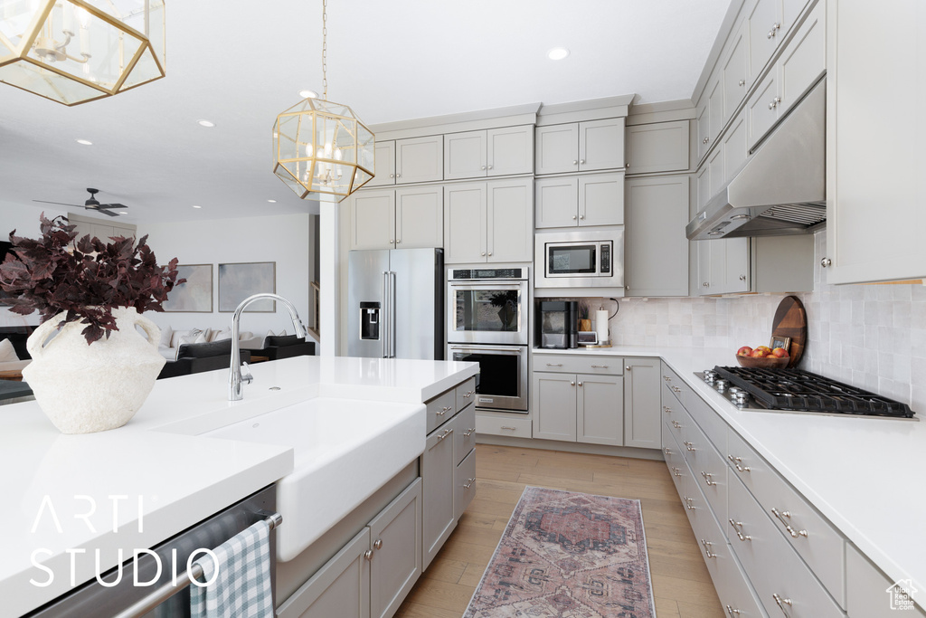 Kitchen with tasteful backsplash, a sink, gray cabinetry, stainless steel appliances, and recessed lighting