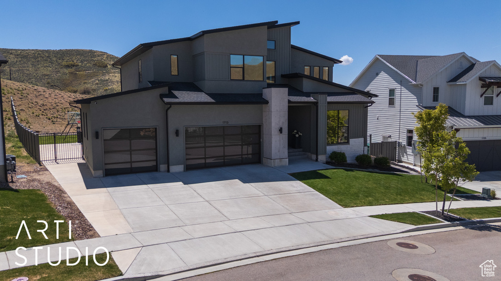 Modern home featuring fence, an attached garage, stucco siding, a mountain view, and concrete driveway