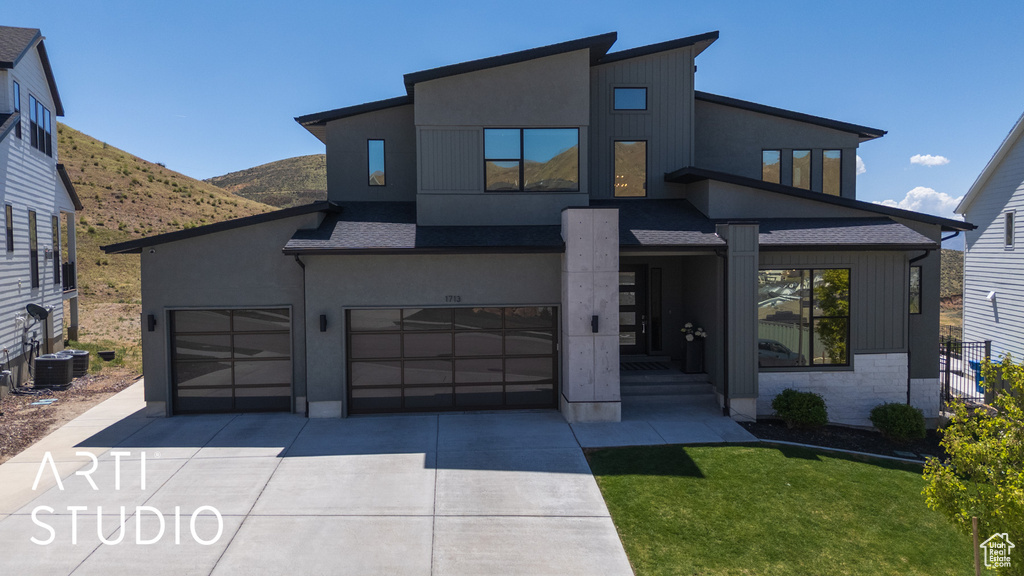 Contemporary home with a garage, a mountain view, stucco siding, and concrete driveway