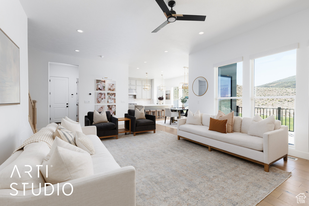 Living area with a healthy amount of sunlight, ceiling fan, and light wood-type flooring